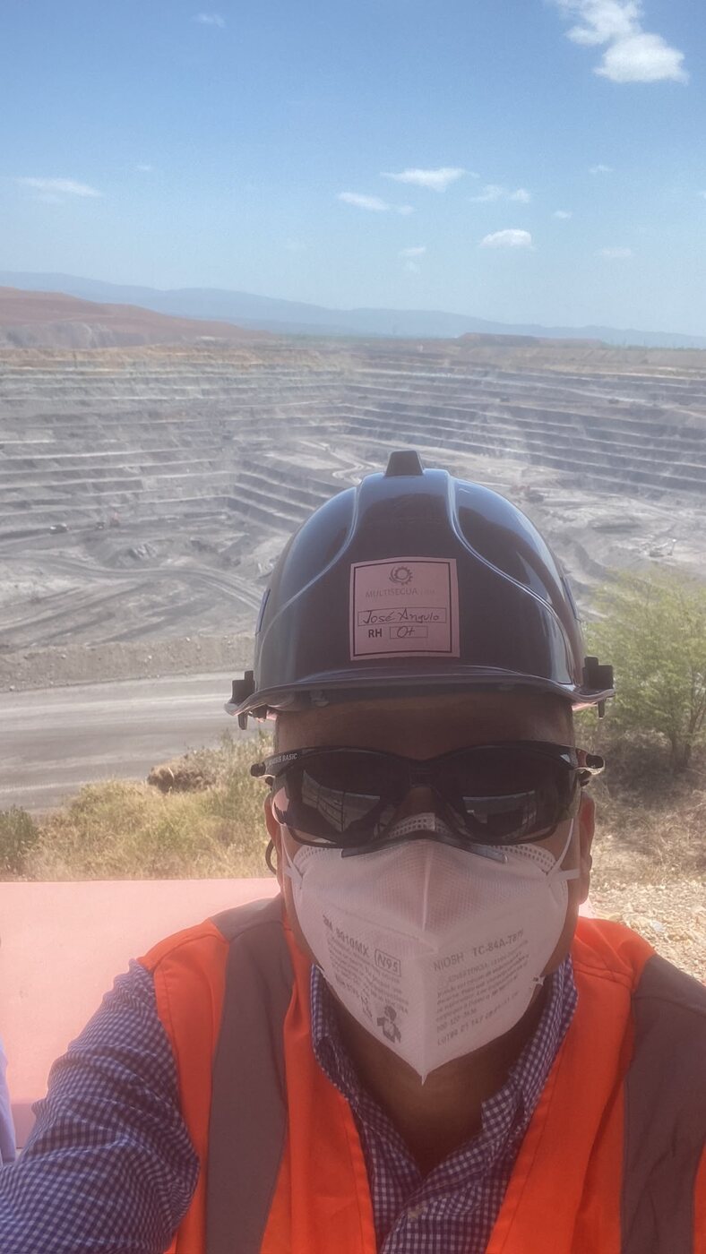 José Nelson Angulo Argote on site above an open-pit mine, wearing helmet and safety vest